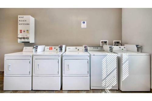 four white washing machines are lined up in a room at OYO Townhouse Beaumont Medical Center Area in Beaumont