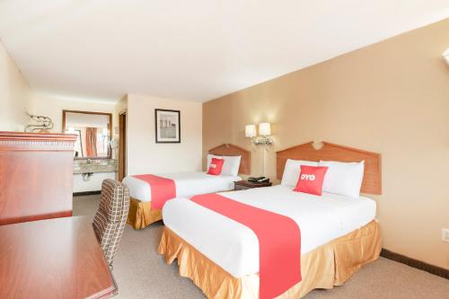 a hotel room with two beds and a table at OYO Hotel Tulsa International Airport in Tulsa
