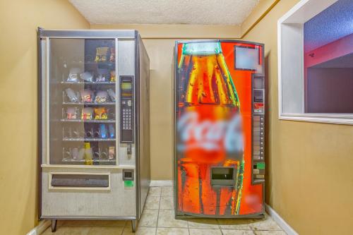 a cocacola soda machine next to a drink cooler at OYO Townhouse Tulsa Woodland Hills in Tulsa