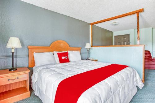 a bedroom with a red and white bed and a mirror at OYO Townhouse Tulsa Woodland Hills in Tulsa