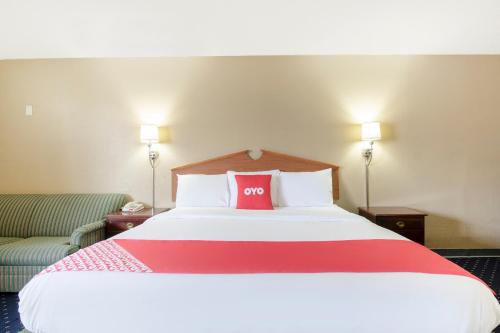 a hotel room with a large bed with a red pillow at OYO Hotel Tulsa International Airport in Tulsa