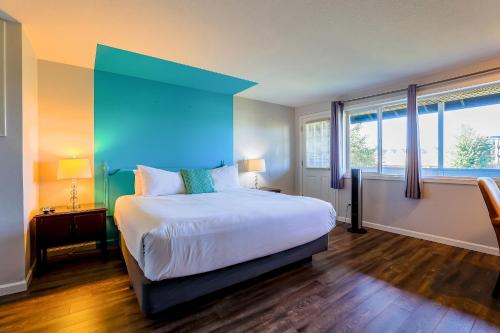 a bedroom with a large bed with a blue headboard at Coast River Inn by OYO Seaside in Seaside