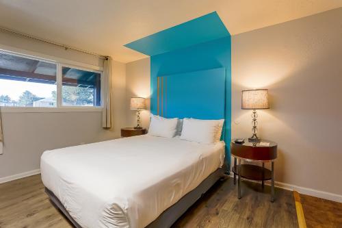 a bedroom with a large bed with a blue headboard at Coast River Inn by OYO Seaside in Seaside