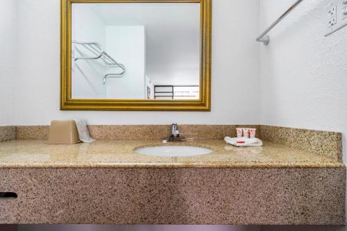 a bathroom counter with a sink and a mirror at OYO Hotel Bossier City LA - Red River in Bossier City