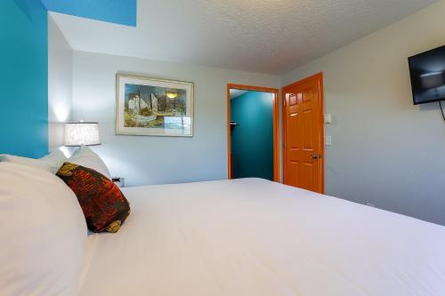 a bedroom with a large white bed with a lamp at Coast River Inn by OYO Seaside in Seaside