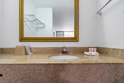 a bathroom counter with a sink and a mirror at OYO Hotel Bossier City LA - Red River in Bossier City