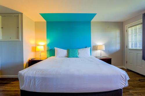 a bedroom with a large white bed with a blue headboard at Coast River Inn by OYO Seaside in Seaside