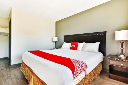 a large bed in a hotel room with a red blanket at OYO Hotel Shreveport Airport North in Shreveport