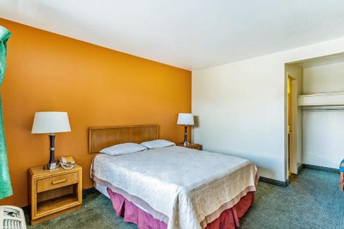 a bedroom with a bed and a yellow wall at OYO Hotel Shreveport Airport North in Shreveport