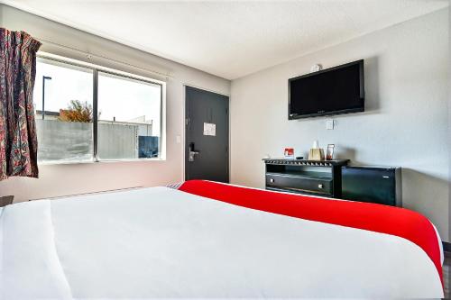 a bedroom with a white bed and a flat screen tv at OYO Hotel Shreveport Airport North in Shreveport