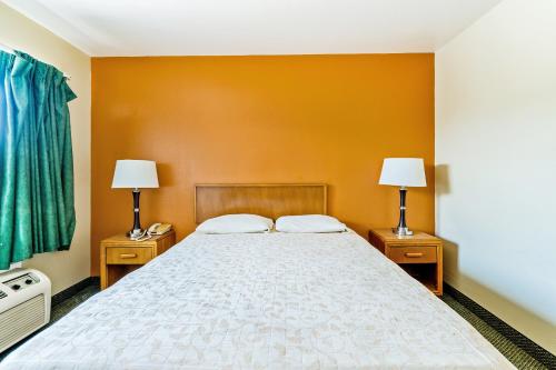 a bedroom with a large bed with two lamps at OYO Hotel Shreveport Airport North in Shreveport