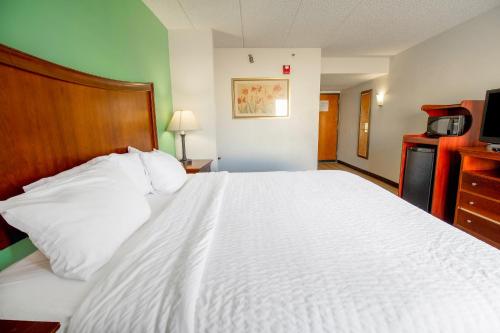 a bedroom with a white bed and a television at Tulsa Square Hotel Central, I-44 By OYO in Tulsa