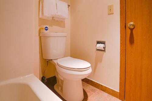 a bathroom with a white toilet and a bath tub at OYO Hotel Redwood Falls near Jackpot Casino in Redwood Falls