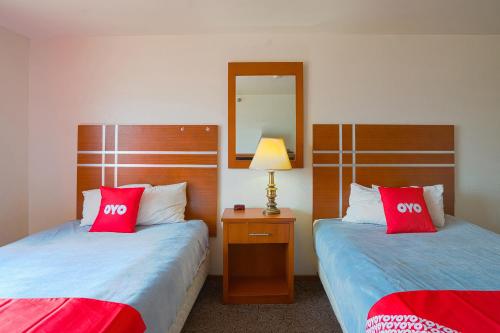 two beds in a hotel room with red pillows at OYO Hotel Redwood Falls near Jackpot Casino in Redwood Falls