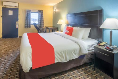 a hotel room with a large bed with a red stripe on it at OYO Hotel Knoxville TN Cedar Bluff I-40 in Knoxville