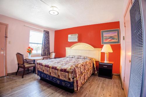 a hotel room with a bed and a table and a window at Sands Motel By OYO El Paso near Airport in El Paso
