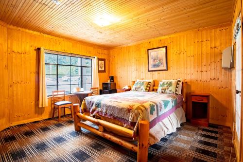 a bedroom with a bed and a table and a window at Lloyd's On The River Country Inn By Oyo in Bryson City
