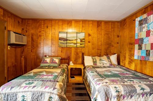 two beds in a room with wooden walls at Lloyd's On The River Country Inn By Oyo in Bryson City