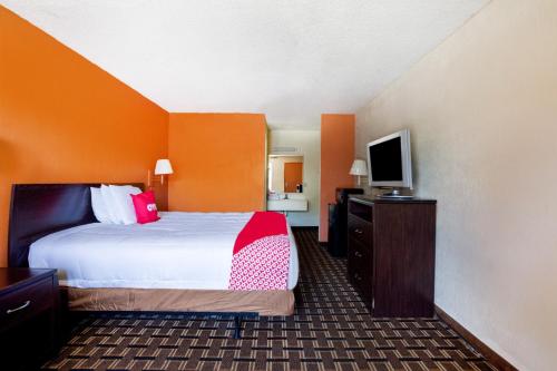 a hotel room with a bed and a flat screen tv at OYO Hotel Pensacola I-10 & Hwy 29 in Pensacola