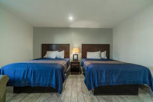 a hotel room with two beds with blue sheets at Pelican Inn by Belvilla Aransas Pass, TX in Aransas Pass