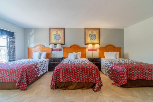 a room with two beds with red and white sheets at Pelican Inn by Belvilla Aransas Pass, TX in Aransas Pass