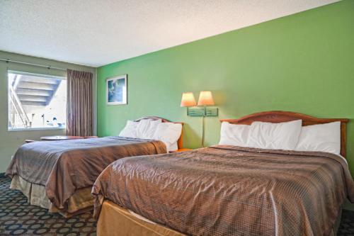 two beds in a hotel room with green walls at Economy Inn By OYO Ashburn in Ashburn
