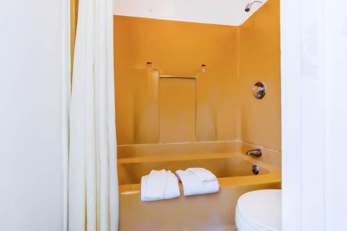 a bathroom with a tub and a toilet and towels at Country Hearth Inn & Suites By OYO Sturgis in Sturgis