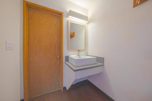 a bathroom with a sink and a mirror and a door at Budget Inn Gladstone By OYO - Portland Clackamas in Gladstone