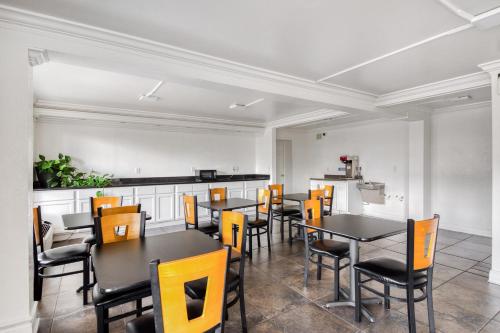 a dining room with black tables and yellow chairs at OYO Hotel Baton Rouge East I-12 Louisiana in Baton Rouge