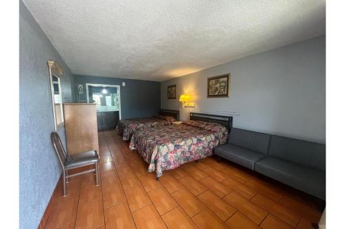 a hotel room with two beds and a couch at La Posada Inn By OYO Brownsville in Brownsville