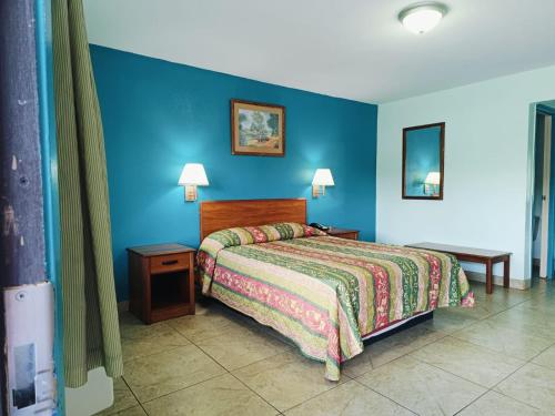 a bedroom with a bed and a blue wall at Budget Inn By OYO Edinburg Hwy 281 in Edinburg
