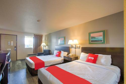 a hotel room with two beds with red and white sheets at OYO Woodland Hotel and Suites in Woodland