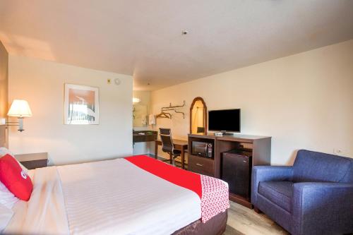 a hotel room with a bed and a chair at OYO Woodland Hotel and Suites in Woodland