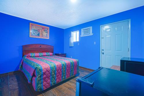 a blue bedroom with a bed and a table at Monterrey Motel Padre Island, Corpus Christi BY OYO in Corpus Christi