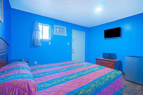 a blue bedroom with a bed and a blue wall at Monterrey Motel Padre Island, Corpus Christi BY OYO in Corpus Christi