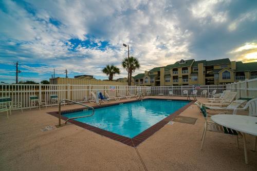 a swimming pool in a resort with chairs and a table at Island Inn By OYO Galveston Beach, TX in Galveston