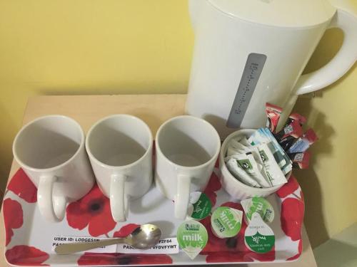 una caja con tres tazas y cucharas en una mesa en London Olympus Hotel, en Londres