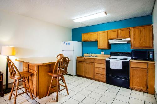a kitchen with wooden cabinets and a table and a refrigerator at OYO Hotel Hutchinson West 4th Ave in Hutchinson