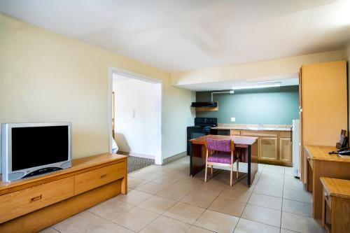 a living room with a tv and a table and a kitchen at OYO Hotel Hutchinson West 4th Ave in Hutchinson