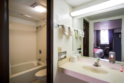 a bathroom with a sink and a toilet and a mirror at OYO Hotel Hutchinson West 4th Ave in Hutchinson