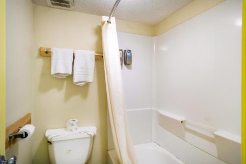 a bathroom with a toilet and a shower with towels at OYO Hotel Hutchinson West 4th Ave in Hutchinson