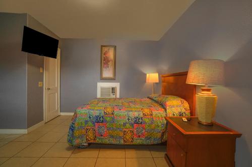 a bedroom with a bed and a lamp and a table at Texana Inn Edna By OYO in Edna