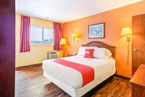 a hotel room with a bed with a red pillow at OYO Hotel Downtown Peoria I-74 in Peoria