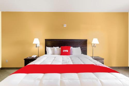 a large bed with a red pillow on it at OYO Hotel Valley View TX, I-35 in Valley View