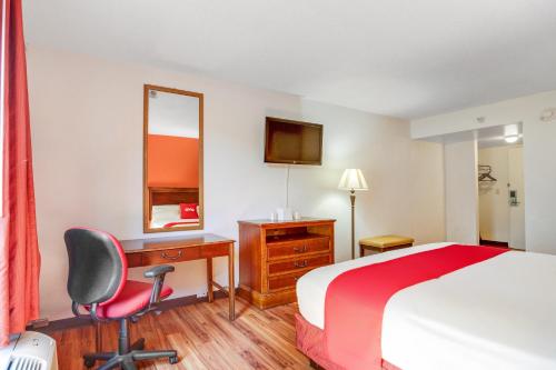 a hotel room with a bed and a desk and a chair at OYO Hotel Mona Lake Muskegon in Muskegon
