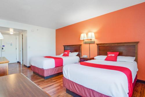 two beds in a hotel room with orange walls at OYO Hotel Mona Lake Muskegon in Muskegon