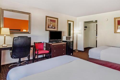a hotel room with a bed and a desk with a television at OYO Townhouse Dodge City KS in Dodge City