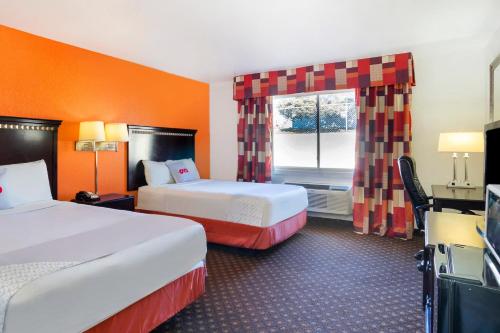 a hotel room with two beds and a window at OYO Townhouse Dodge City KS in Dodge City