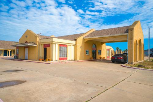 a large yellow building with a car parked in a parking lot at Aransas Bay Inn & Suites Corpus Christi by OYO in Aransas Pass