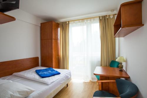 um quarto com uma cama, uma secretária e uma janela em OW Posejdon Jastarnia - blisko morza i nad zatoką em Jastarnia